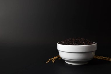 Siyah arka planda beyaz bir seramik kasede Tayland siyah pirinç çileği..