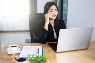 Ev kavramından çalış. Asyalı güzel işgüzar kadın dizüstü bilgisayar ve telefon kullanıyor..