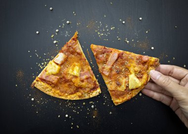 El çıtır çıtır bir pizza seçiyor ve siyah ahşap bir masada baharatlar var. Üst görünüm.