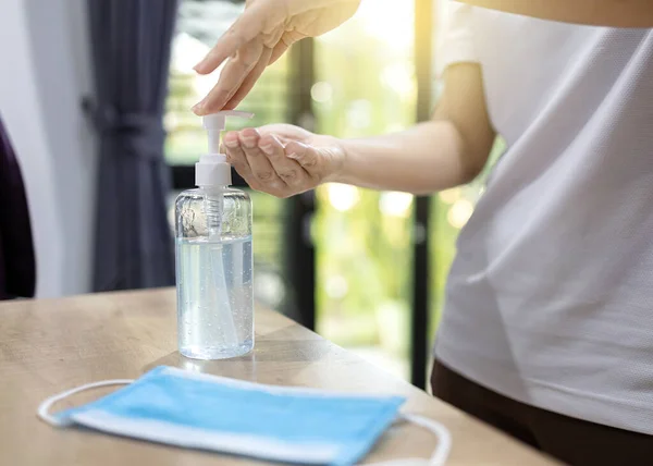 Woman pressing gel to wash hands from bottles and a sanitary mask.placed on table.