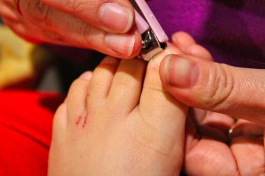 Tırnak ve parmak manikürü. Anne, küçük bir makasla tırnağı kesip, sevgi ve özenle temizler..