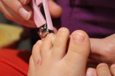 Tırnak ve parmak manikürü. Anne, küçük bir makasla tırnağı kesip, sevgi ve özenle temizler..