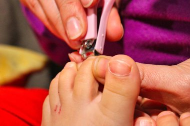 Tırnak ve parmak manikürü. Anne, küçük bir makasla tırnağı kesip, sevgi ve özenle temizler..