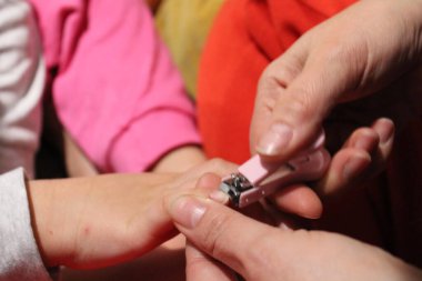 Tırnak ve parmak manikürü. Anne, küçük bir makasla tırnağı kesip, sevgi ve özenle temizler..