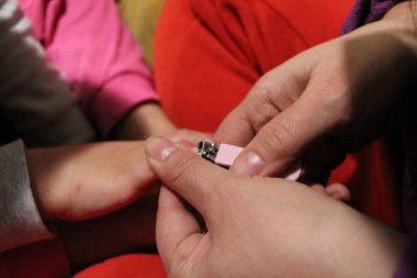 Tırnak ve parmak manikürü. Anne, küçük bir makasla tırnağı kesip, sevgi ve özenle temizler..
