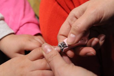 Tırnak ve parmak manikürü. Anne, küçük bir makasla tırnağı kesip, sevgi ve özenle temizler..