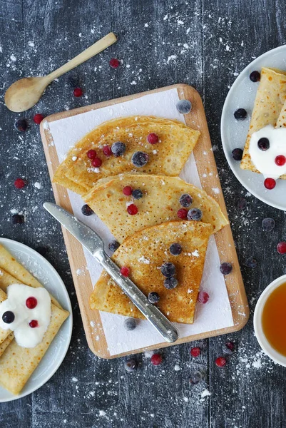 Healthy spelt homemade crepes with berries on a dark background - top view