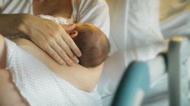 Anne yeni doğmuş bebeği emzirir ve kucaklar.
