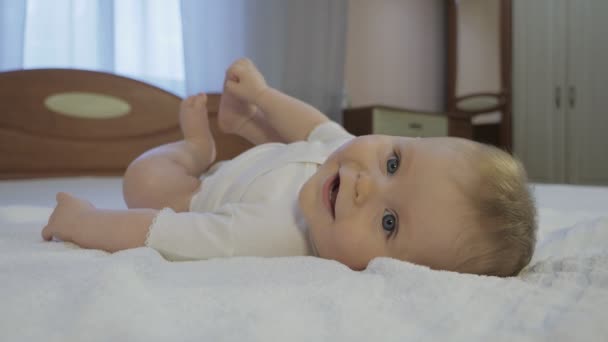 Yatakta uzanmış mavi gözlü şirin bir bebek. — Stok video