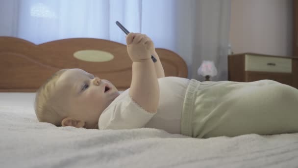 Nyfiken baby med en smartphone i handen — Stockvideo