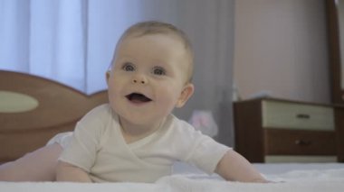 Cute toddler lies on diaper in bedroom