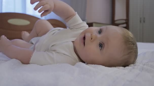 Bebê bonito com olhos azuis deitado na cama — Vídeo de Stock