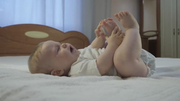 Schattige baby huilen op het bed. — Stockvideo