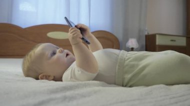 Mavi gözlü şirin bebek akıllı telefona bakıyor.