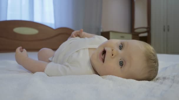 Lindo bebé con ojos azules acostado en la cama — Vídeo de stock