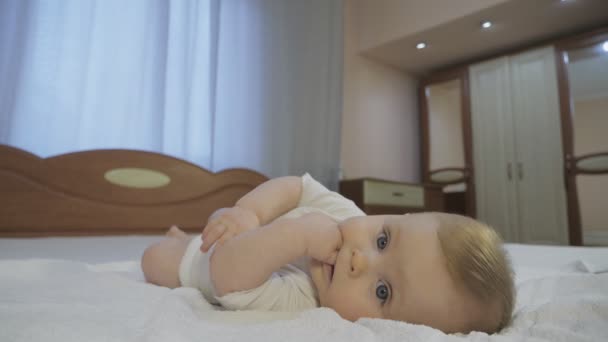 Kék szemű kisgyermek, az ágyon fekvő szőke hajjal — Stock videók