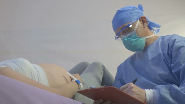 Молодая беременная женщина осматривается хирургом — стоковое видео