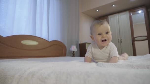 Carino bambino con gli occhi azzurri sdraiato in camera da letto — Video Stock