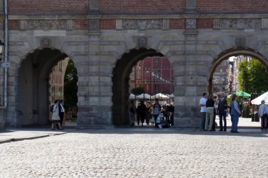 Arka arkaya güneş gören eski kasaba meydanı binaları, Gdansk, Polonya 'daki pazar meydanındaki insanlar üç kemerli yollar.
