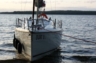 Gün batımında yelkenli yelkenli ölü bir göle demirlemiş, yaklaşmakta.