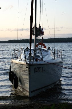 Gün batımında yelkenli yelkenli ölü bir göle demirlemiş, yaklaşmakta.