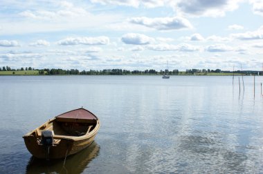 Tekne gölde demirli. Sudaki bulutların yansıması.