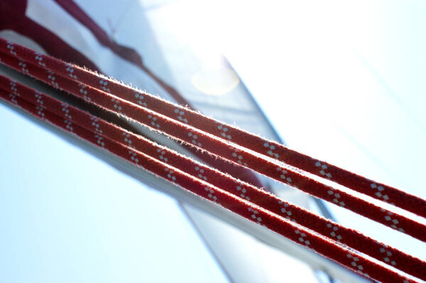 Красные парусные канаты с белым парусом на заднем плане
