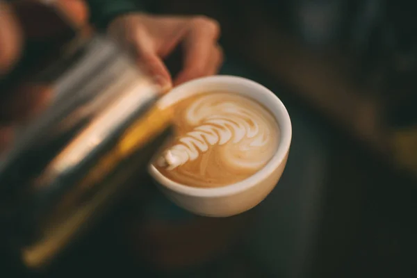 Barista fait latte art dans une tasse de café . — Photo