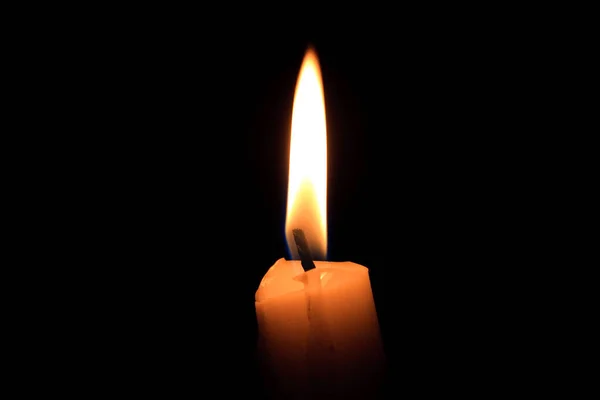 A single burning candle, isolated with black background, candle wick, closeup, macro. Hot fire flame in the dark night.