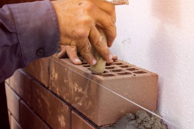 Duvarcı ustası bir mala ile hafifçe dokunarak tuğla bırakır. İnşaatı İşi