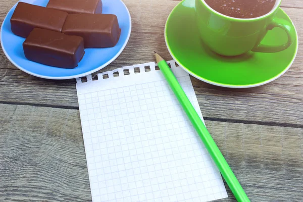 记事本 茶托上的巧克力和旧木桌上的咖啡杯 — 免费的图库照片