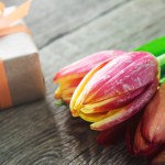 Tulipas rosa e caixa de presente na mesa de madeira