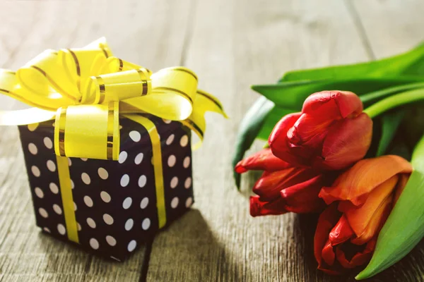 stock image Red tulips and gift box on wooden table