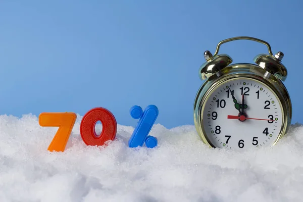 The concept of winter discounts. Clock and numbers of 70 percent in the snow, on blue background