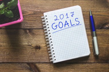 Amaçları ahşap bir masaya bir not defteri ve bir bitki bir kolu ile yazılır