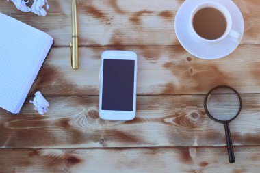 Smartphone ve bir fincan kahve ile ahşap bir masa üzerinde finansal araçlar