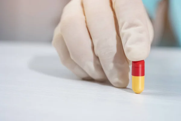 Red and yellow tablet in the doctor \'s hand, close up