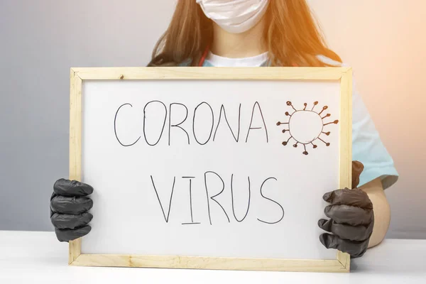 The doctor holds a marker Board with the inscription Coronavirus