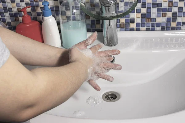 女の子はバスルームのタイル張りの背景にあるタップから水の下で手を洗う — ストック写真