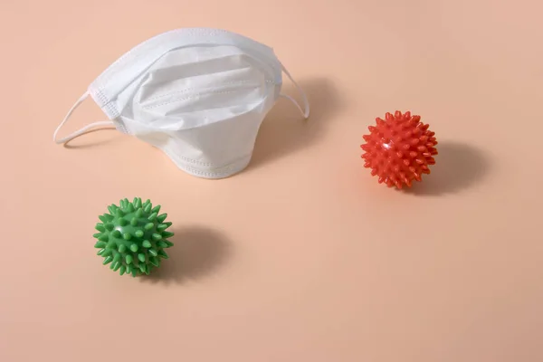 桃の背景に緑と赤の医療用マスクと2つのコロナウイルス分子 コロナウイルスからの保護の概念 — ストック写真