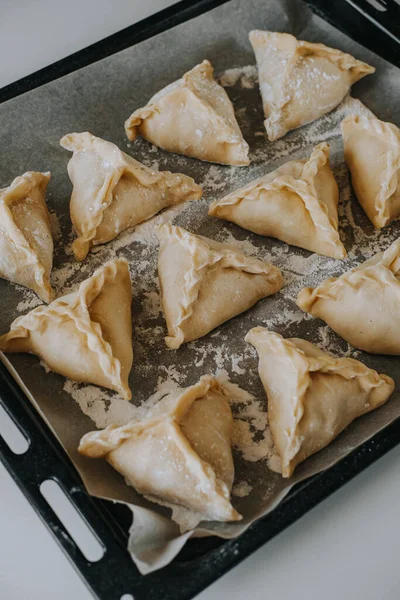 Triangular pies lie on a baking tray. National dish — Stock Image Triangular pies lie on a baking tray. National dish Royalty Free Stock Photos