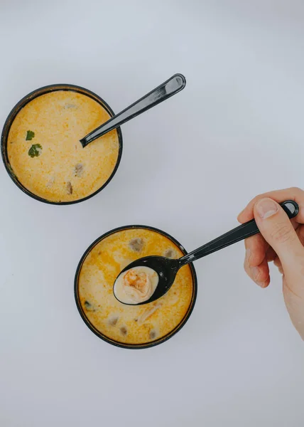 Un homme tient une cuillère avec la soupe Tom Yam. Livraison de nourriture — Photo