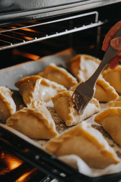 Triangular pies lie on a baking tray. National dish — Stock Image Triangular pies lie on a baking tray. National dish Stock Photo