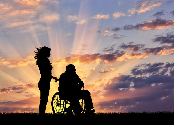Silhouette of a nurse caring for a disabled person in a wheelchair