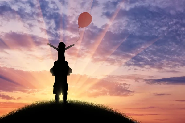 Zonsondergang kind zit op de vader en het houden van een ballon op heuvel — Stockfoto
