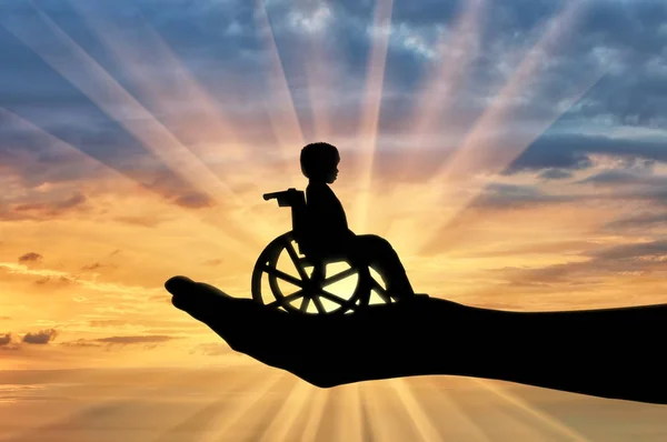 Παιδί με ειδικές ανάγκες σε μια αναπηρική καρέκλα στο χέρι ενός ανθρώπου — Φωτογραφία Αρχείου