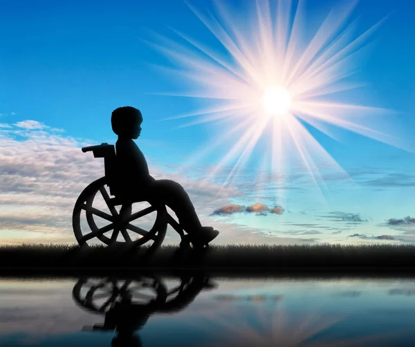Мальчик в инвалидном кресле и отражение в день воды — стоковое фото