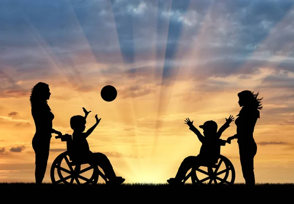 Meninos felizes em cadeira de rodas jogar bola e enfermeiros por do sol — Fotografia de Stock