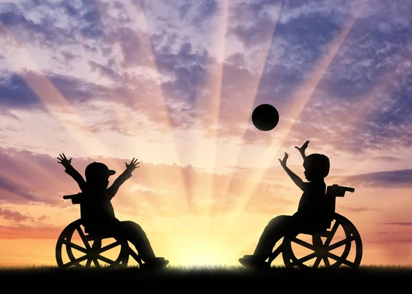 Дети-инвалиды играют в мяч на закате — стоковое фото