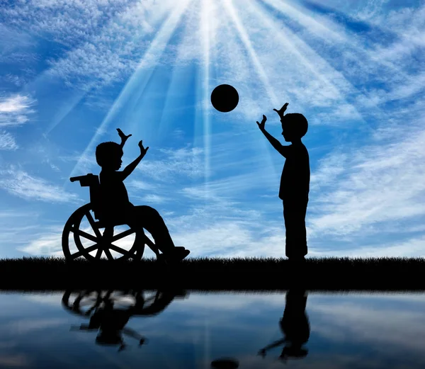 Szczęśliwy chłopiec na wózku inwalidzkim, grając z chłopcem w piłkę — Zdjęcie stockowe